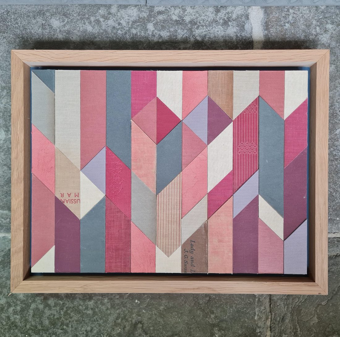 A chevron piece built from old book spines, float-mounted in a natural oak tray.