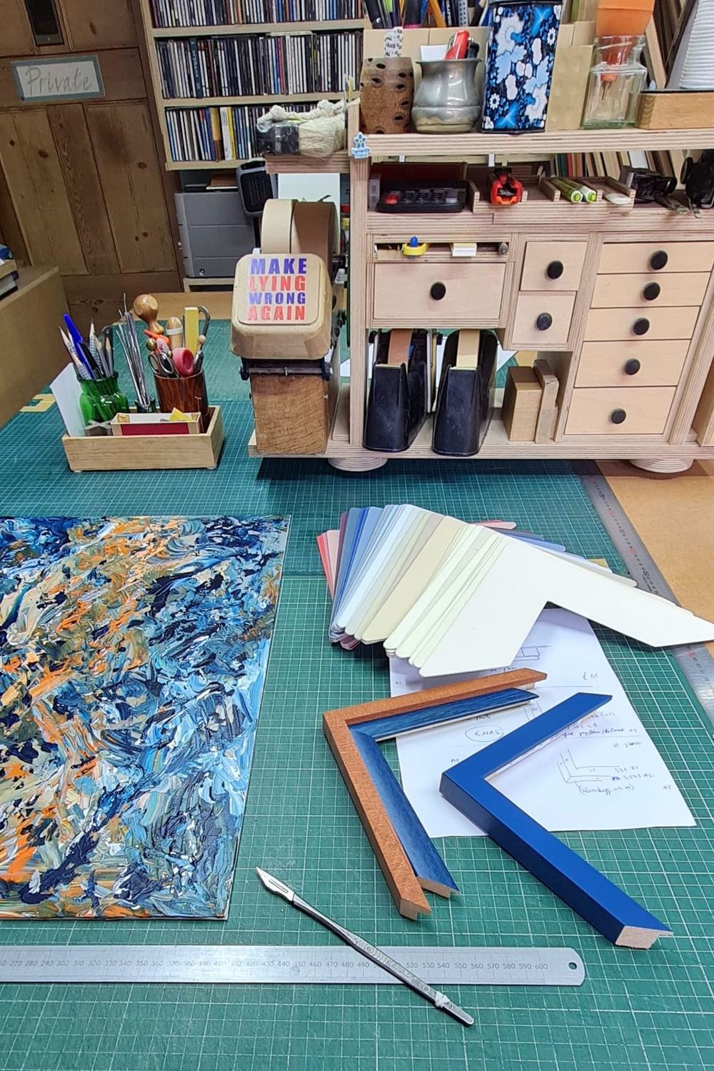 The Bamber the Framer workbench, a green cutting mat with two corner moulding samples, stacked mount board and tools